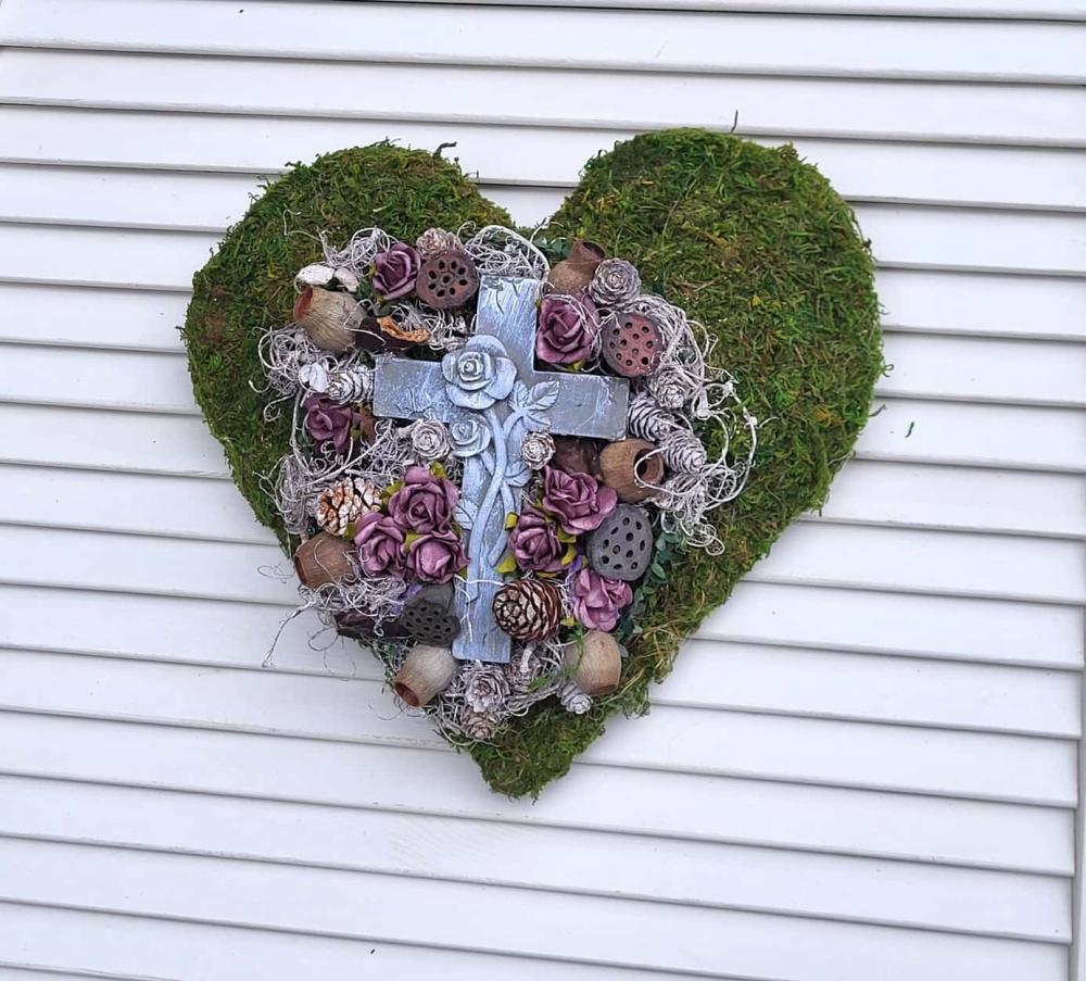 Grabherz aus Moos und vielen kleinen bordeauxfarbigen Rosen und einem gr0ßen Kreuz in der Mitte