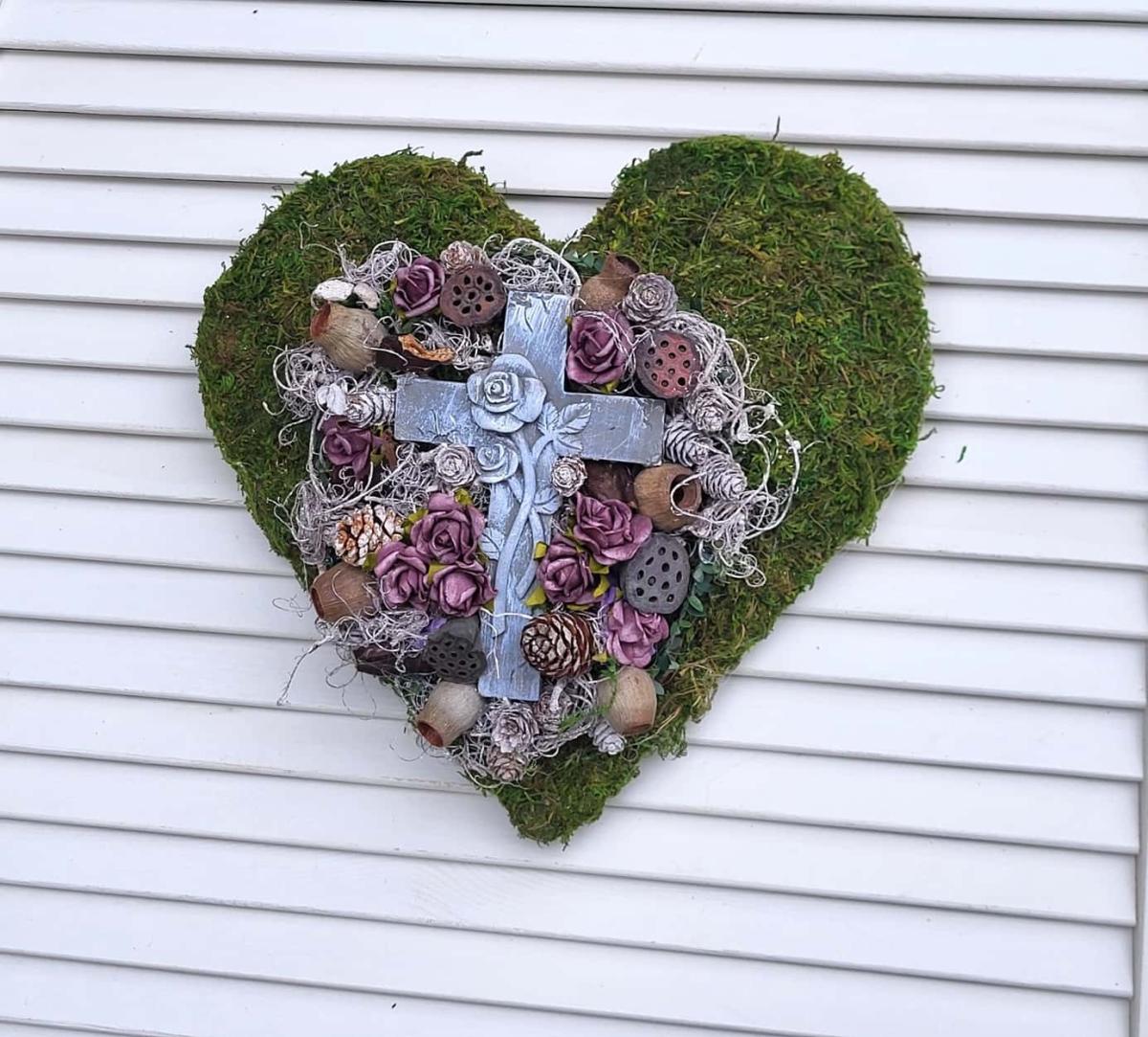 Grabherz aus Moos und vielen kleinen bordeauxfarbigen Rosen und einem gr0ßen Kreuz in der Mitte